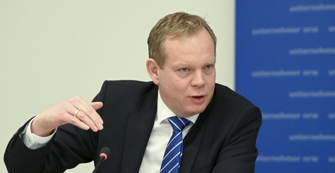 Mann mit Geste vor dem unternehmer nrw Banner