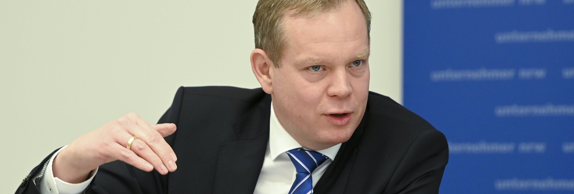 Mann mit Geste vor dem unternehmer nrw Banner